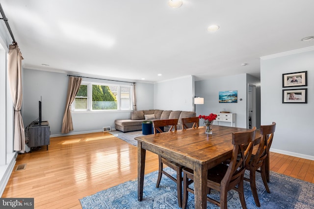 dining room featuring light wood finished floors, visible vents, and crown molding