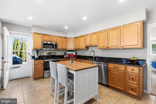 kitchen with stainless steel appliances, butcher block countertops, a sink, and backsplash