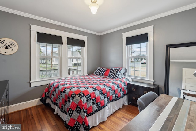 bedroom with crown molding, multiple windows, baseboards, and wood finished floors