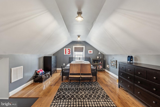 bedroom with light wood-type flooring, baseboards, visible vents, and vaulted ceiling