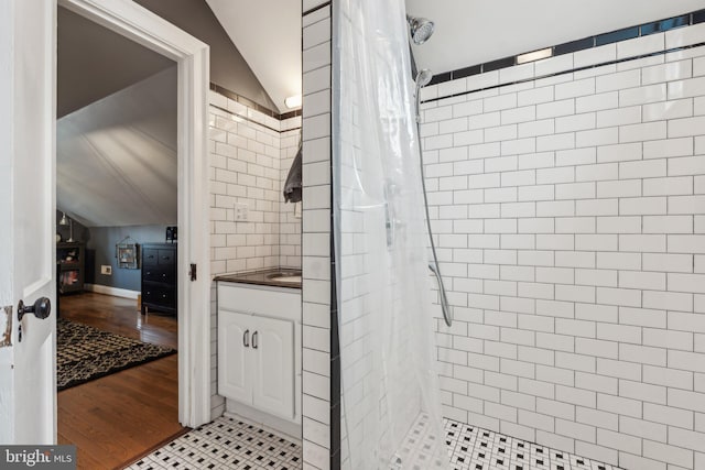 full bath with vaulted ceiling, wood finished floors, vanity, and a shower stall