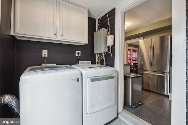 laundry area featuring washing machine and dryer, cabinet space, and dark tile patterned flooring