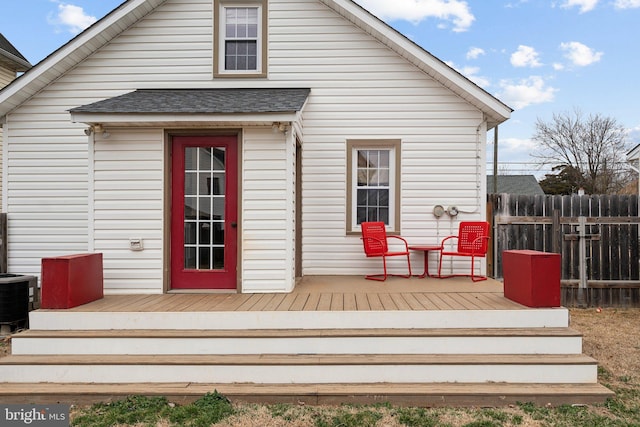 exterior space featuring central AC unit, a shingled roof, fence, and a wooden deck