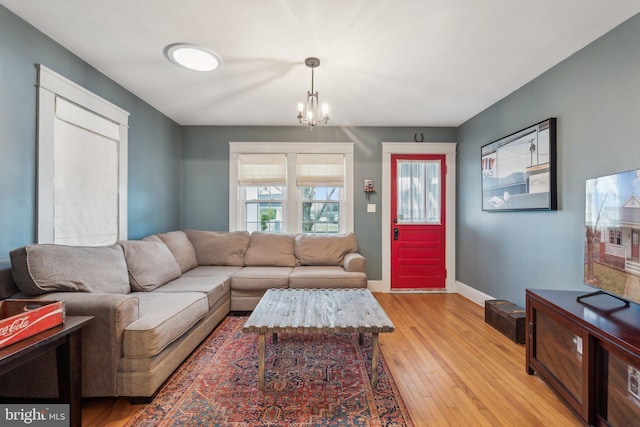 living area featuring light wood-style flooring, baseboards, and an inviting chandelier