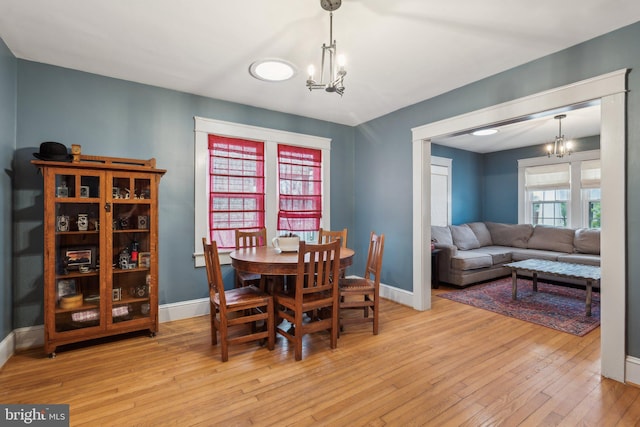 dining space with an inviting chandelier, baseboards, and hardwood / wood-style floors