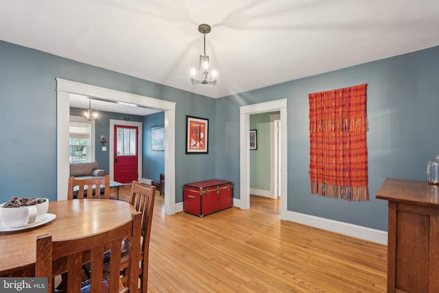 dining area with light wood-style flooring, baseboards, and an inviting chandelier