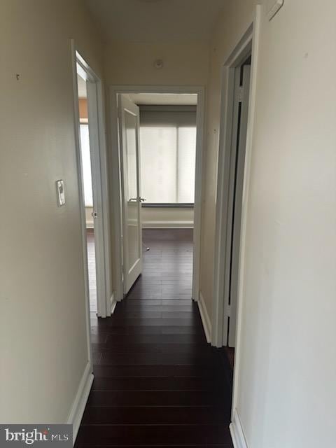 hallway with dark wood-style flooring and baseboards