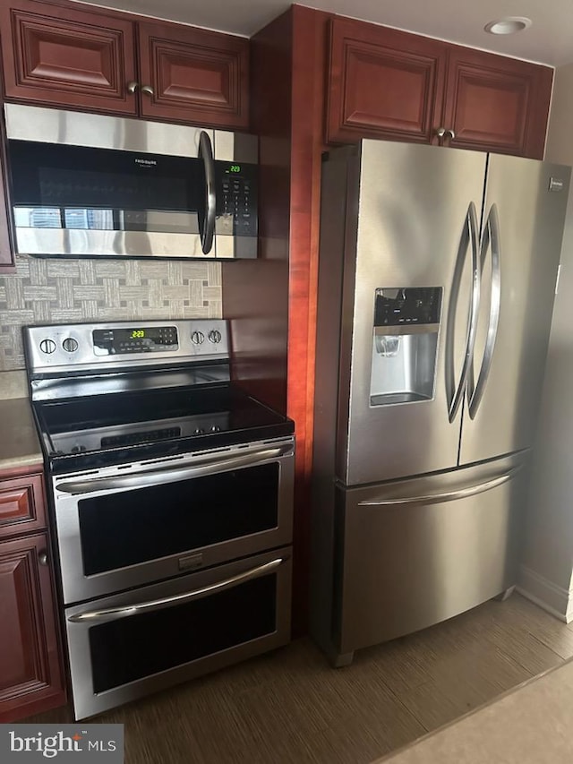 kitchen featuring reddish brown cabinets, tasteful backsplash, and appliances with stainless steel finishes