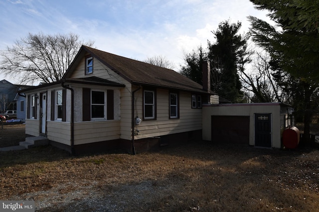 view of side of home featuring entry steps, an outdoor structure, and driveway