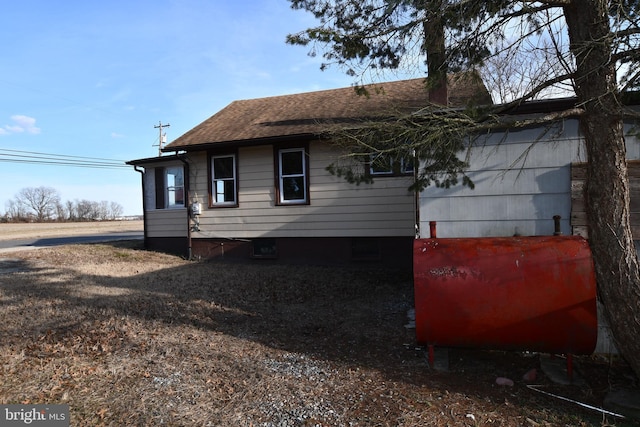 rear view of property with roof with shingles and heating fuel