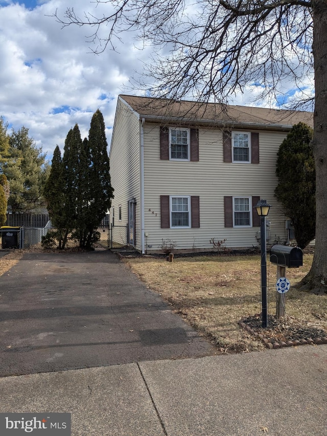 view of front of home with aphalt driveway, a gate, and fence