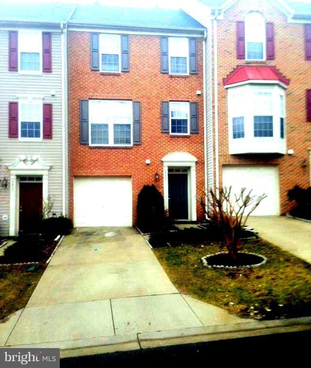 view of front of home with an attached garage, concrete driveway, and brick siding