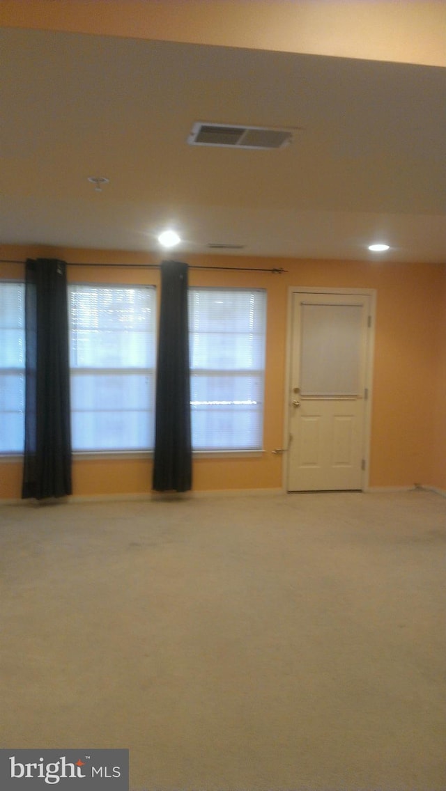 carpeted empty room featuring visible vents and baseboards