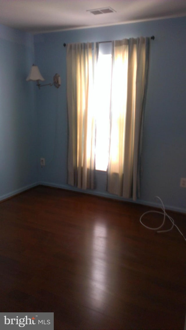 empty room with visible vents, plenty of natural light, and wood finished floors