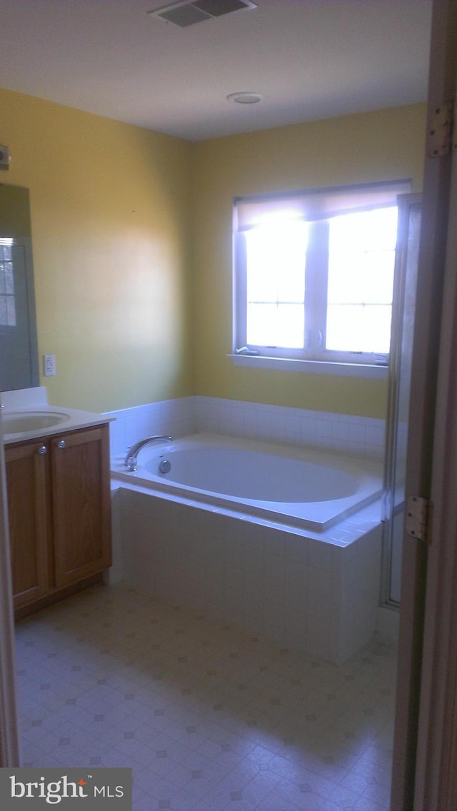 full bathroom featuring visible vents, vanity, and a bath