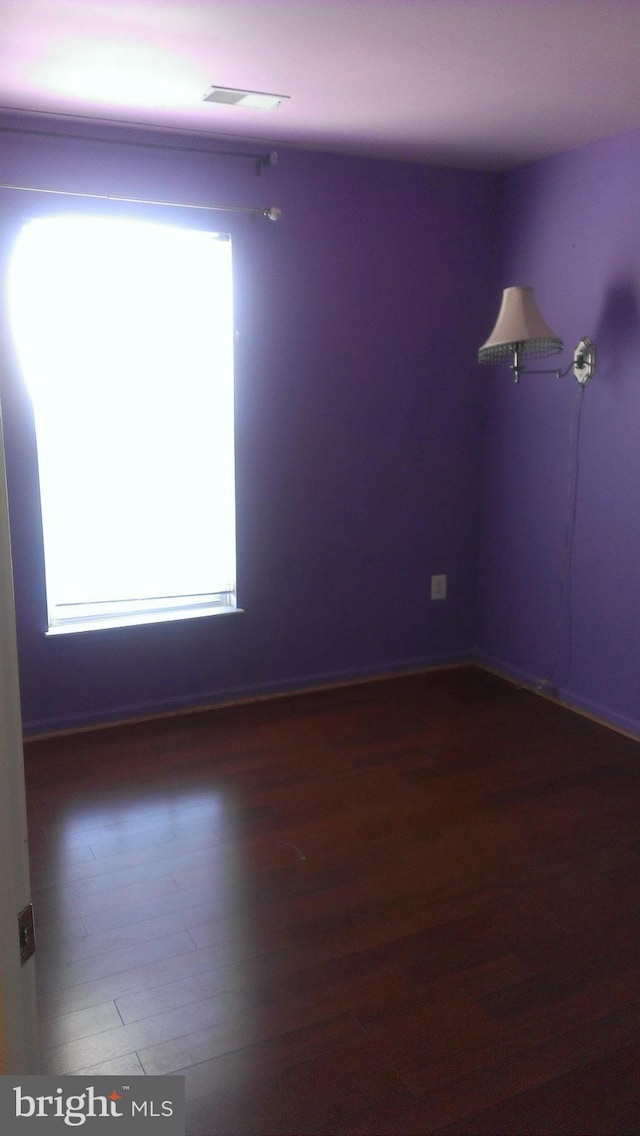 spare room with plenty of natural light, visible vents, and wood finished floors