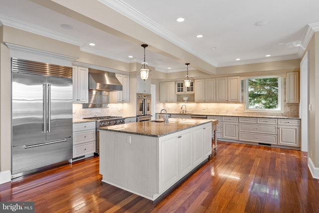1900 Carrollton Rd, Annapolis, MD 21409 - kitchen featuring high quality appliances, light stone counters, wall chimney exhaust hood, tasteful backsplash, and dark wood-type flooring