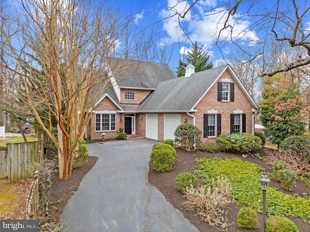 traditional-style house with brick siding, a shingled roof, fence, driveway, and an attached garage