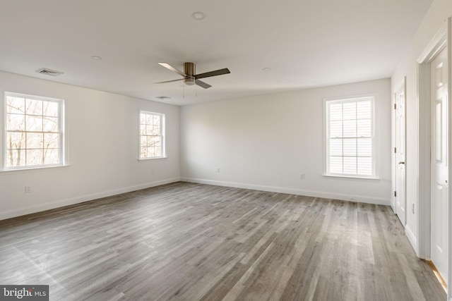 unfurnished room featuring a ceiling fan, baseboards, visible vents, and light wood finished floors