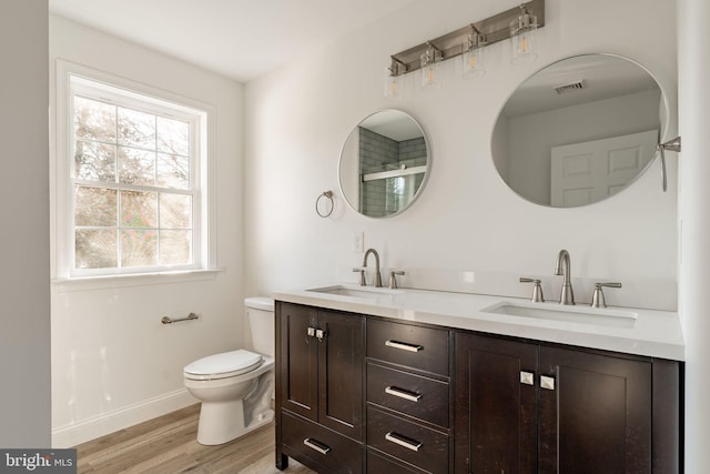 bathroom with wood finished floors, a sink, toilet, and baseboards