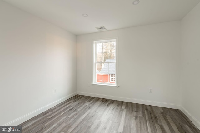 empty room featuring visible vents, baseboards, and wood finished floors