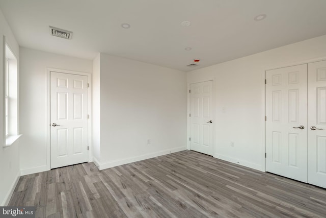 unfurnished bedroom featuring baseboards, visible vents, and wood finished floors