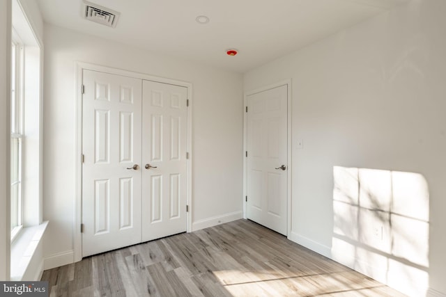 unfurnished bedroom with baseboards, a closet, visible vents, and wood finished floors