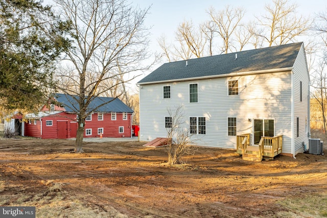 rear view of property featuring central AC unit and roof with shingles