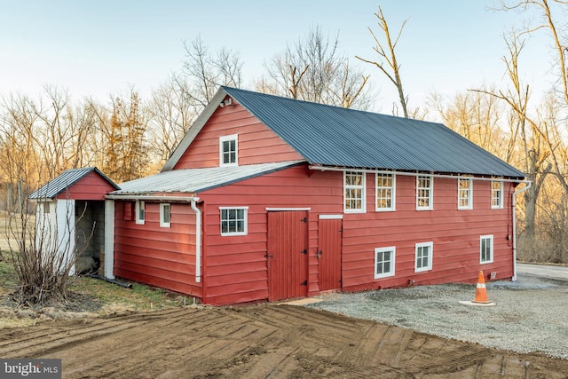 view of side of home with an outbuilding, metal roof, a barn, and driveway