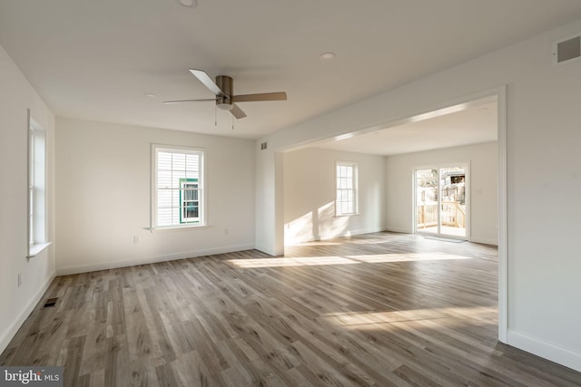 empty room featuring visible vents, ceiling fan, baseboards, and wood finished floors