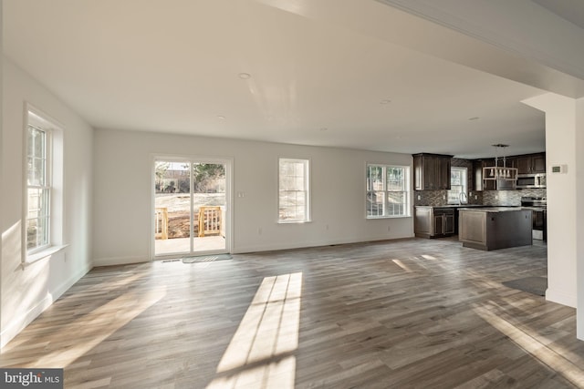 unfurnished living room featuring light wood-style floors, baseboards, and a sink