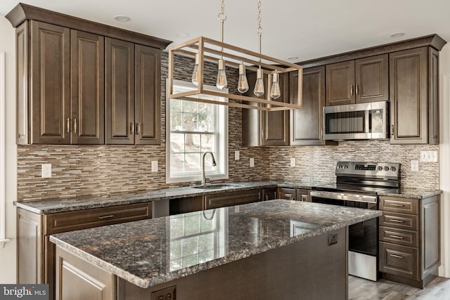 kitchen featuring appliances with stainless steel finishes, backsplash, a sink, and dark brown cabinetry