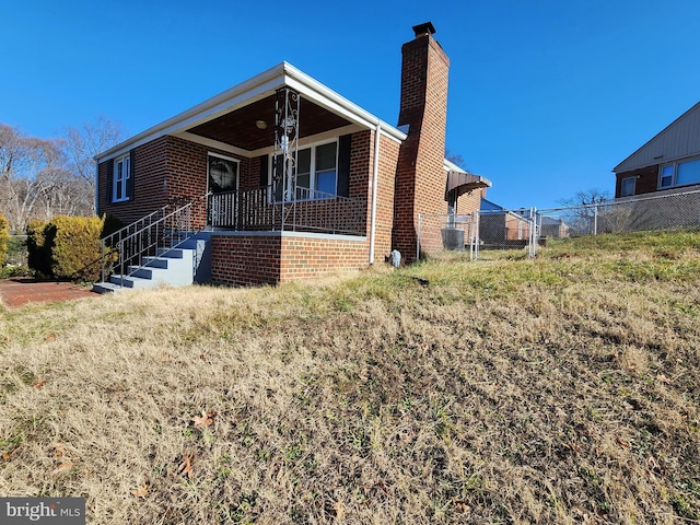 view of front facade with a chimney, a gate, fence, a porch, and brick siding