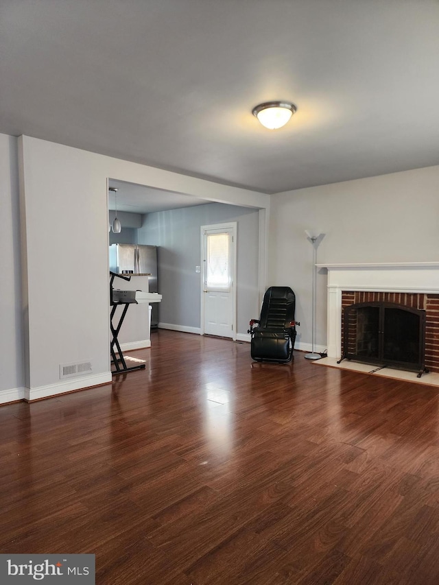 unfurnished room featuring a fireplace, wood finished floors, visible vents, and baseboards