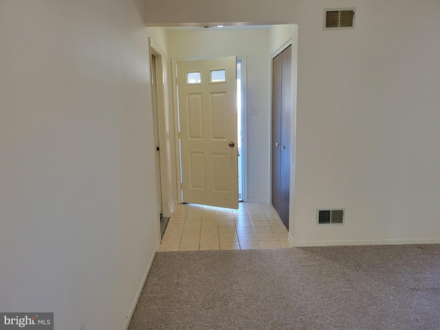 foyer with baseboards, light tile patterned flooring, visible vents, and light colored carpet