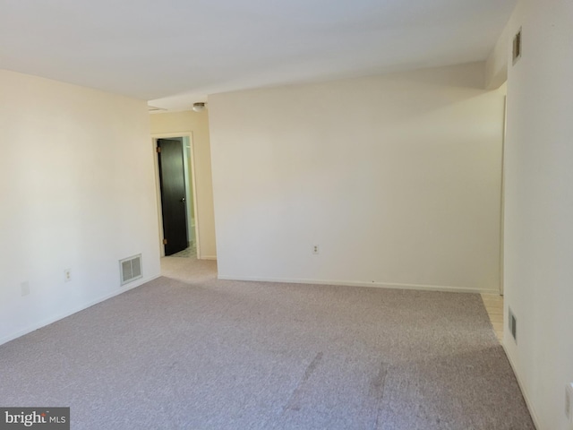 unfurnished room with baseboards, visible vents, and light colored carpet