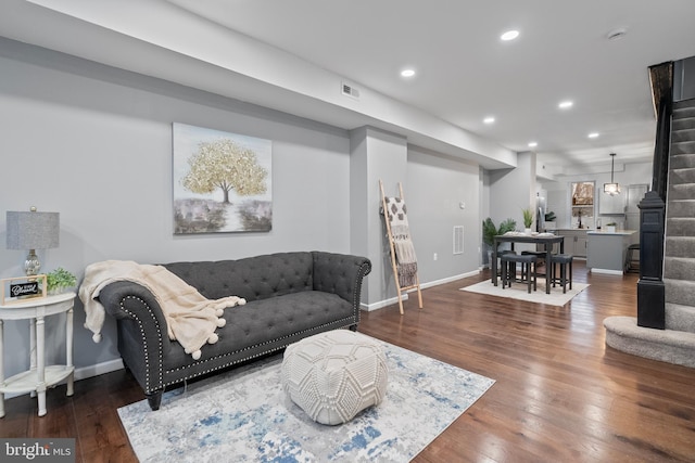 living area featuring recessed lighting, visible vents, wood finished floors, baseboards, and stairs