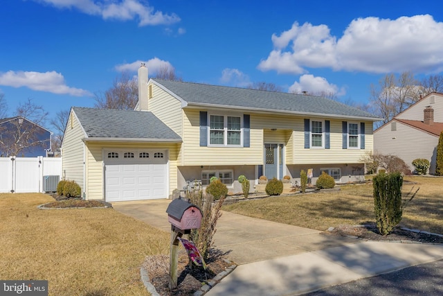 raised ranch with cooling unit, a garage, fence, concrete driveway, and a chimney