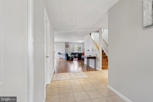 entryway featuring stairs, light tile patterned floors, and baseboards