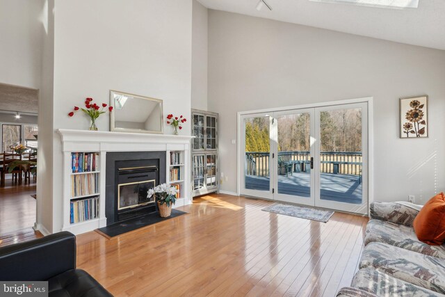 living area with a fireplace with flush hearth, high vaulted ceiling, wood-type flooring, rail lighting, and baseboards