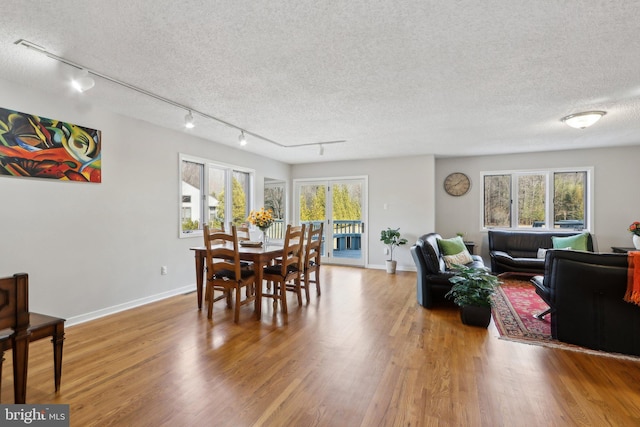 dining space featuring wood finished floors, baseboards, a wealth of natural light, and a textured ceiling