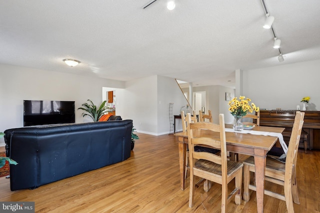 dining space featuring stairway, a textured ceiling, track lighting, and light wood finished floors