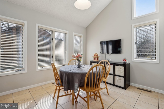 dining room with light tile patterned floors, visible vents, baseboards, and lofted ceiling