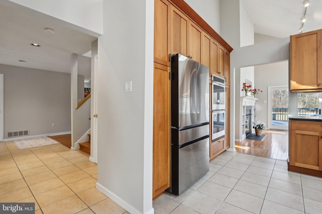 kitchen featuring visible vents, track lighting, appliances with stainless steel finishes, a fireplace, and light tile patterned floors