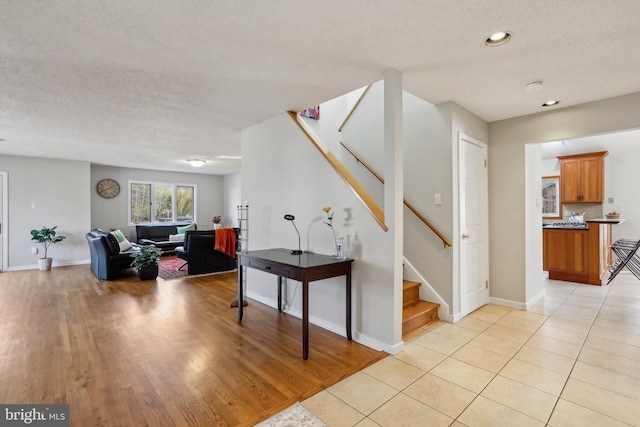 interior space with baseboards, a textured ceiling, light wood-style flooring, and stairs