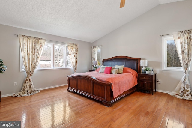 bedroom featuring baseboards, ceiling fan, vaulted ceiling, light wood-style floors, and a textured ceiling