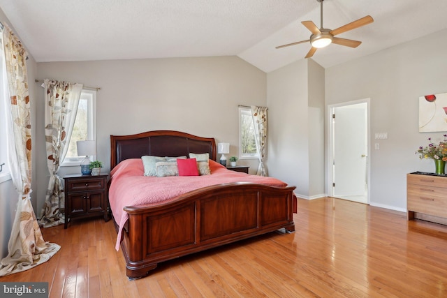 bedroom featuring vaulted ceiling, multiple windows, light wood-type flooring, and ceiling fan