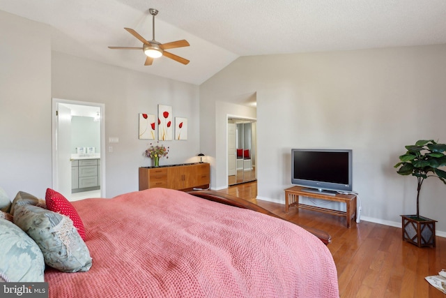 bedroom featuring wood finished floors, connected bathroom, baseboards, ceiling fan, and vaulted ceiling