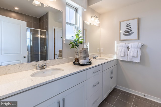 full bathroom featuring double vanity, a stall shower, tile patterned flooring, and a sink