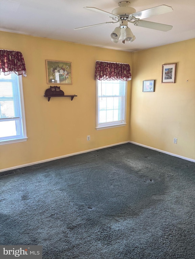 unfurnished room featuring a ceiling fan, dark carpet, and baseboards